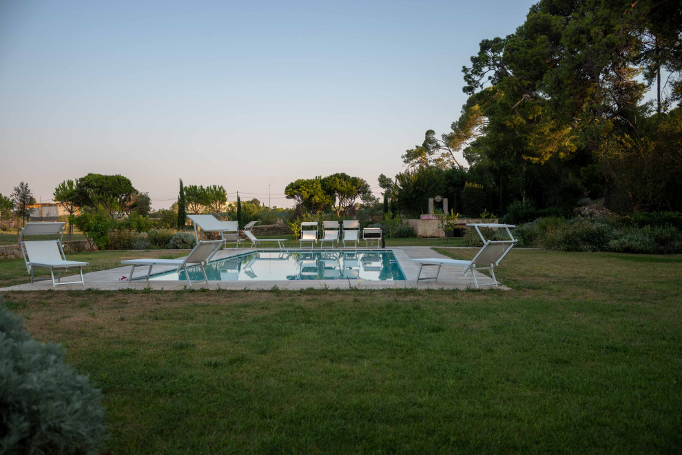 Стильный дизайн: большой прямоугольный ландшафтный бассейн на заднем дворе в средиземноморском стиле с покрытием из каменной брусчатки - последний тренд