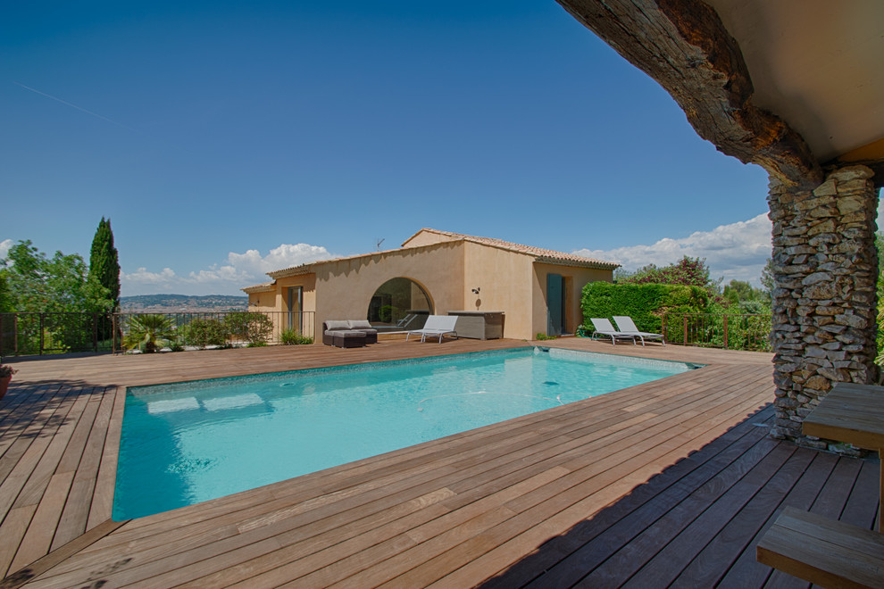 Idées déco pour un grand Abris de piscine et pool houses arrière méditerranéen rectangle avec une terrasse en bois.