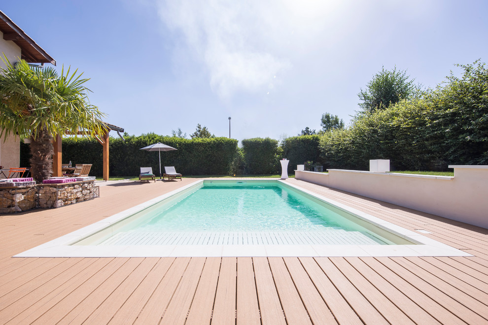 Cette image montre une grande piscine minimaliste rectangle avec une terrasse en bois.