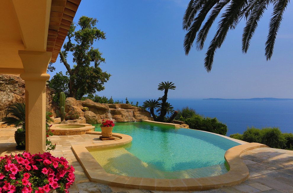 Idee per una piscina a sfioro infinito mediterranea personalizzata di medie dimensioni e dietro casa con una vasca idromassaggio e pavimentazioni in pietra naturale