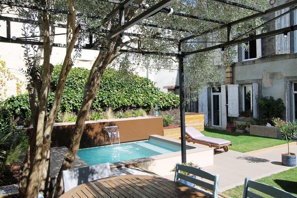 Cette image montre une petite piscine hors-sol méditerranéenne sur mesure avec un point d'eau, une cour et une terrasse en bois.