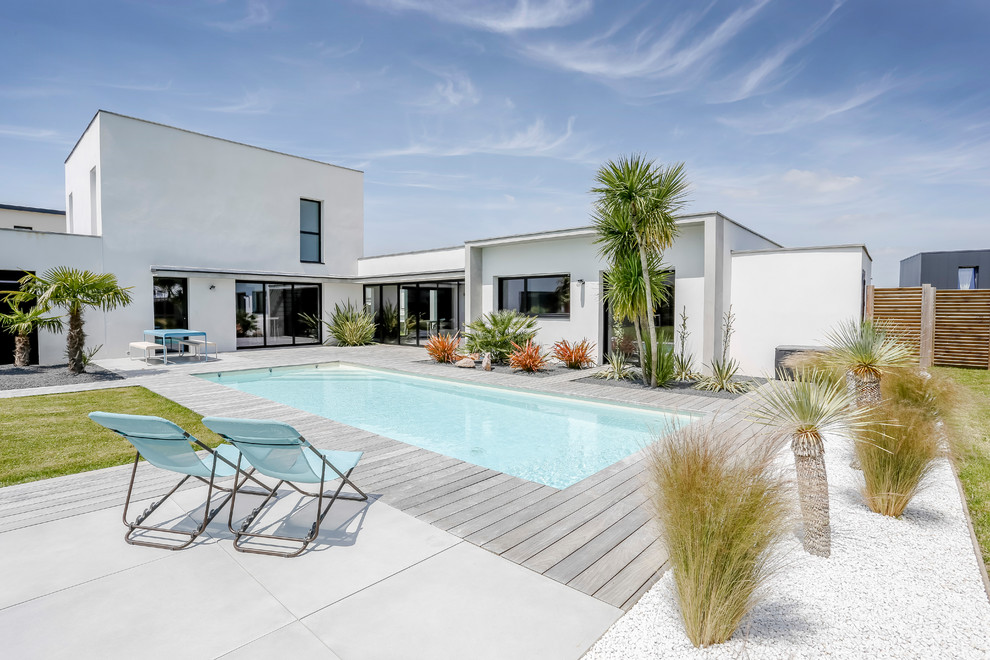 Exemple d'une piscine arrière moderne de taille moyenne et rectangle avec une terrasse en bois.