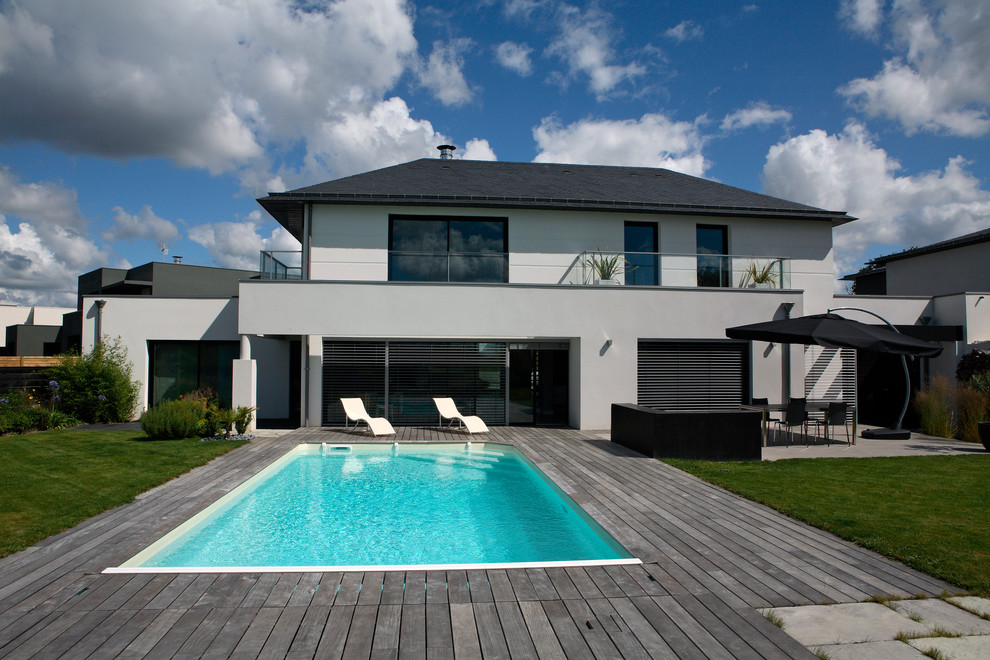 Idée de décoration pour une piscine arrière urbaine de taille moyenne et rectangle avec une terrasse en bois.