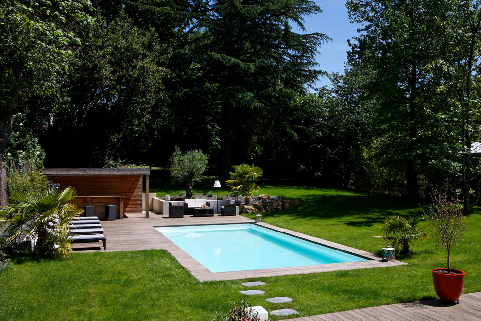 Aménagement d'une piscine moderne de taille moyenne et rectangle avec une terrasse en bois.