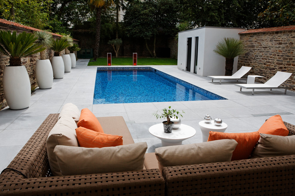 Modelo de piscina contemporánea de tamaño medio rectangular en patio trasero con losas de hormigón