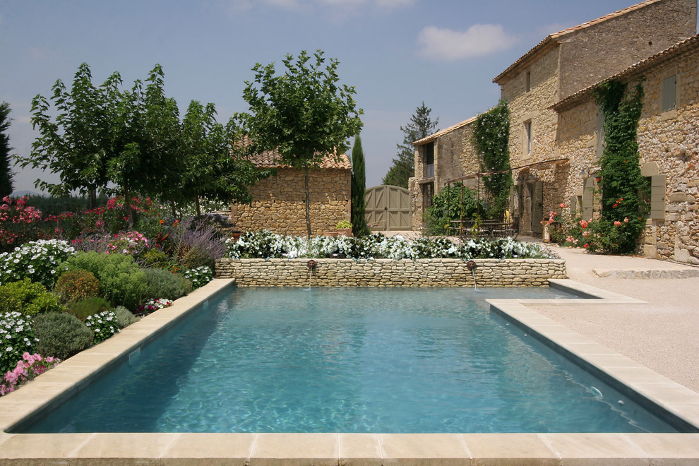 Modelo de piscina con fuente de estilo de casa de campo de tamaño medio rectangular con gravilla