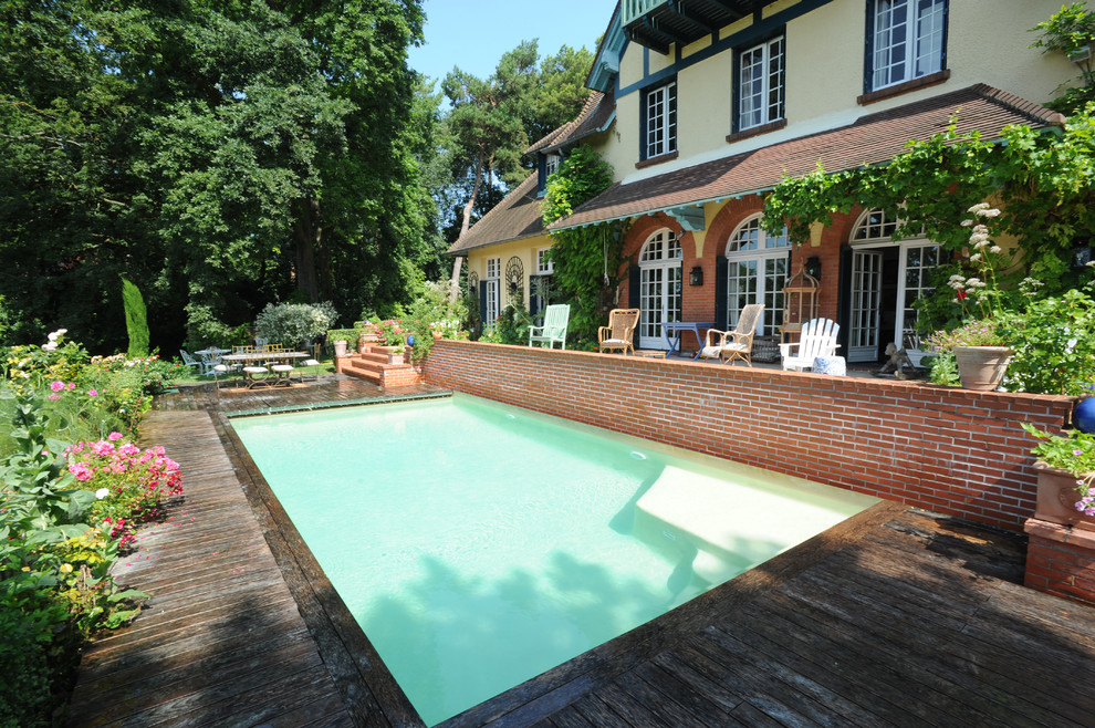 Diseño de piscina de estilo de casa de campo de tamaño medio rectangular en patio trasero con entablado
