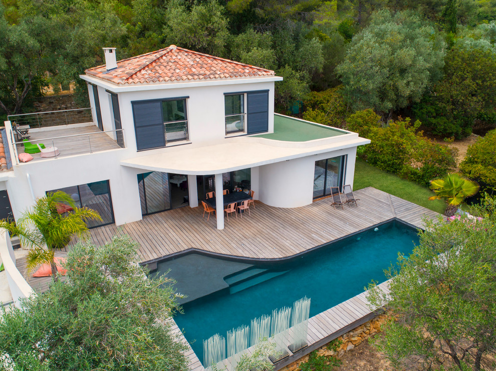 Réalisation d'une piscine design de taille moyenne et sur mesure avec une terrasse en bois.
