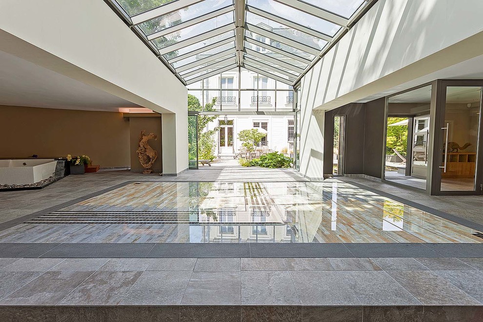 Idée de décoration pour une grande piscine intérieure design rectangle avec des pavés en pierre naturelle.