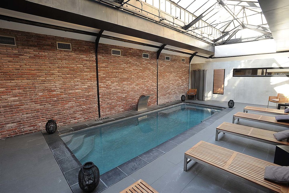 Ejemplo de piscina con fuente industrial grande rectangular y interior con suelo de baldosas