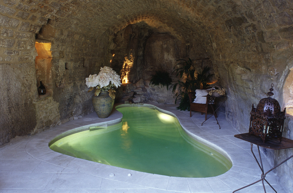 This is an example of a small traditional indoor custom shaped swimming pool in Montpellier with natural stone paving.