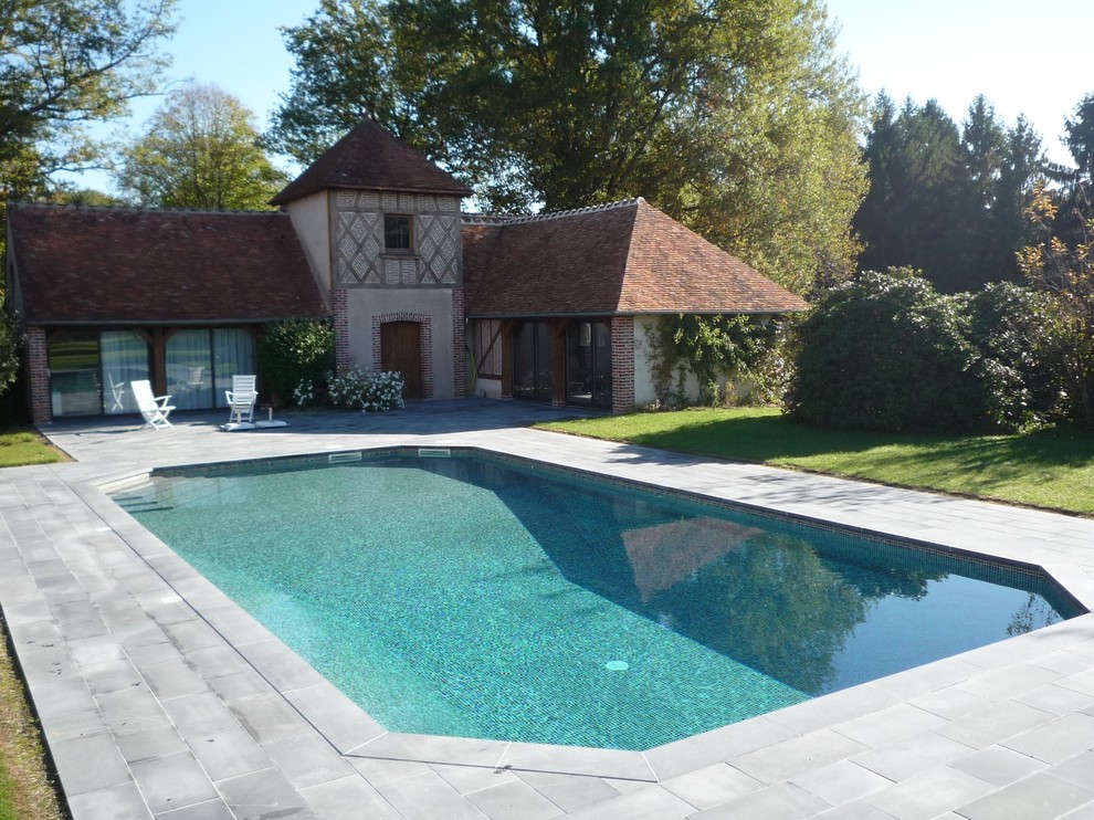Modelo de piscina alargada campestre grande rectangular en patio con suelo de baldosas
