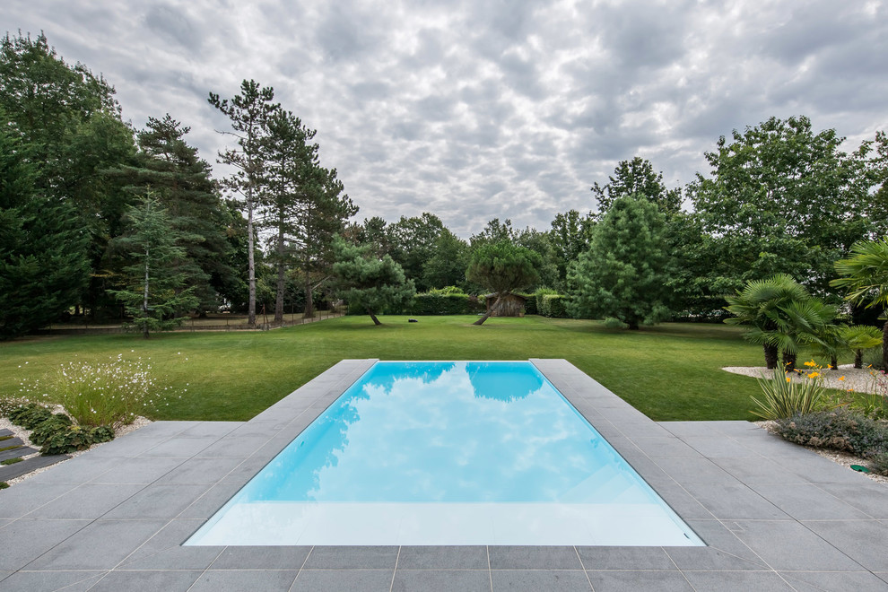 Mid-sized minimalist rectangular infinity pool photo in Other