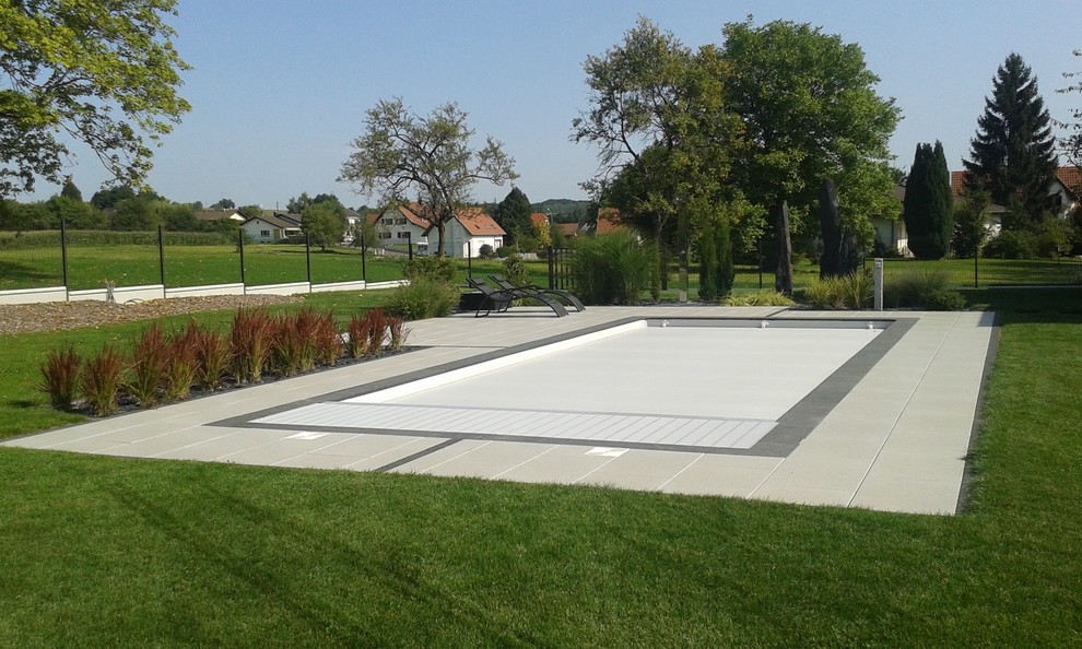 Mittelgroßes Modernes Sportbecken hinter dem Haus in rechteckiger Form mit Betonplatten in Straßburg