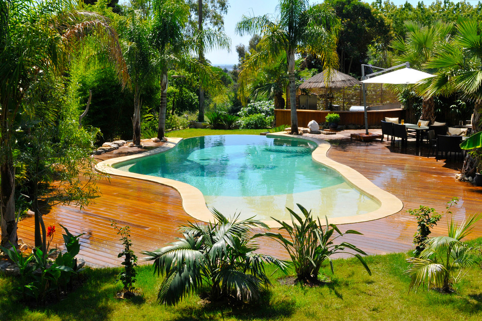 Cette image montre une piscine ethnique sur mesure avec une terrasse en bois.