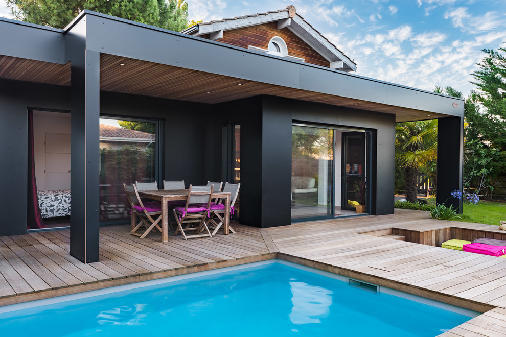 Ejemplo de casa de la piscina y piscina contemporánea rectangular en patio trasero con entablado