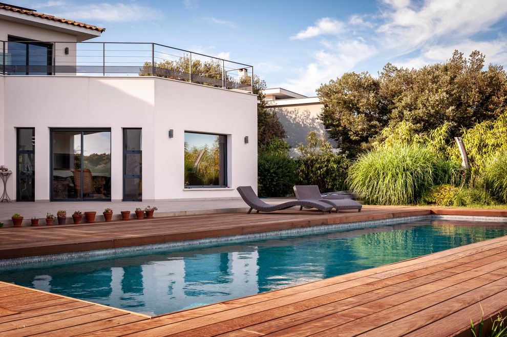 Aménagement d'une piscine arrière méditerranéenne rectangle avec une terrasse en bois.