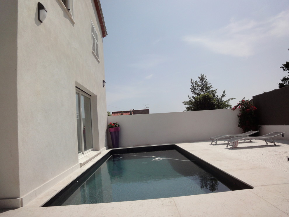 Ejemplo de piscina con fuente natural actual de tamaño medio rectangular en patio lateral con adoquines de piedra natural