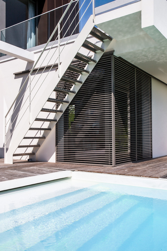 Inspiration pour une grande piscine à débordement et arrière minimaliste sur mesure avec une terrasse en bois.
