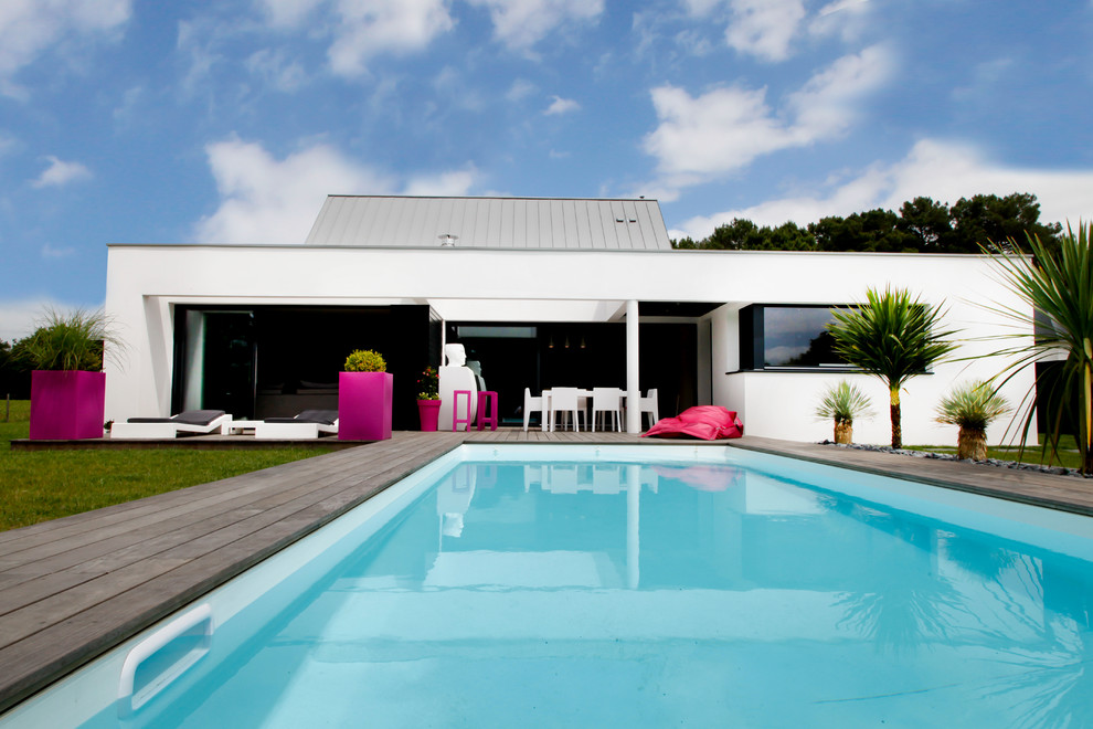 Pool - large contemporary backyard rectangular pool idea in Rennes with decking