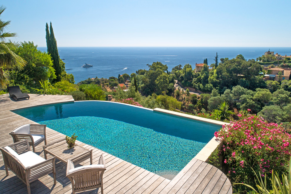 Photo of a mediterranean custom shaped infinity swimming pool with decking.