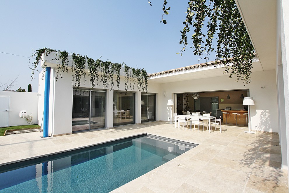 Modelo de piscina alargada moderna de tamaño medio rectangular en patio con adoquines de piedra natural