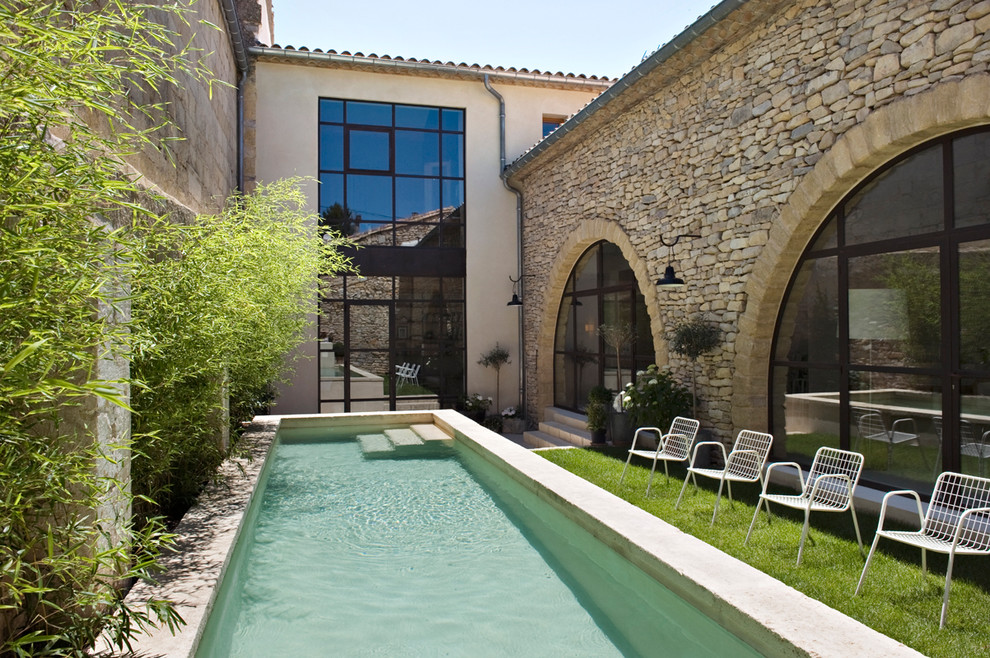 Imagen de piscina alargada actual de tamaño medio rectangular en patio con adoquines de piedra natural