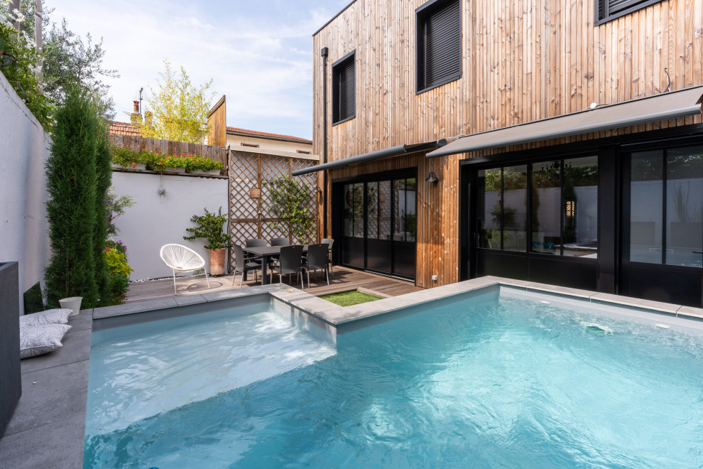 Réalisation d'une petite piscine hors-sol tradition en L avec une cour et une terrasse en bois.