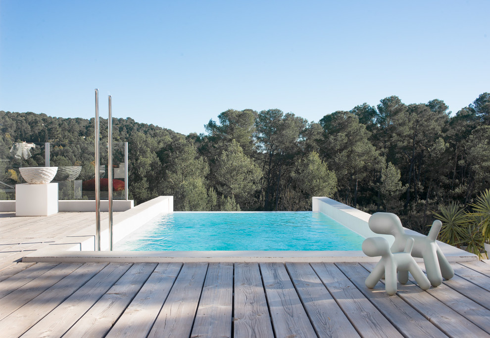 Idées déco pour une piscine à débordement et arrière contemporaine de taille moyenne et rectangle avec une terrasse en bois.
