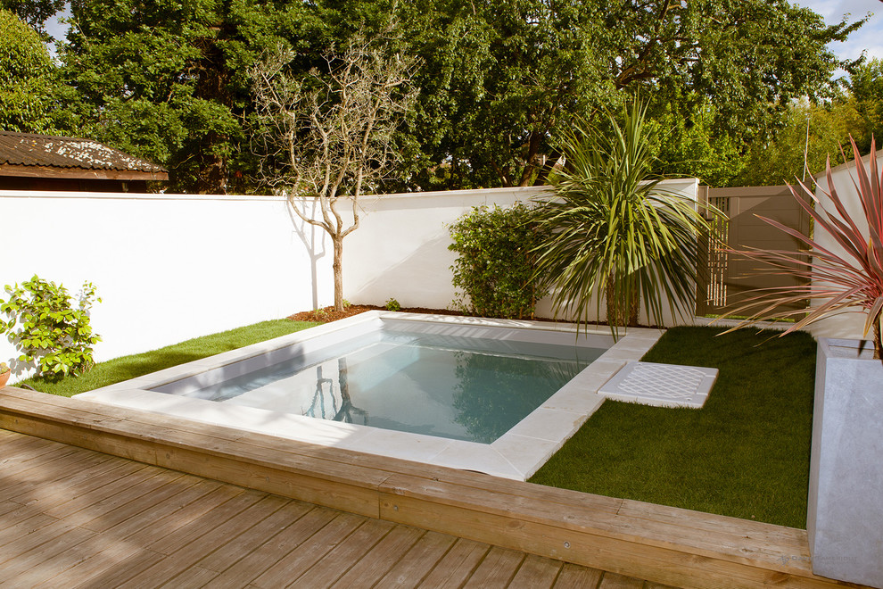 Ejemplo de piscina actual pequeña a medida en patio trasero con entablado
