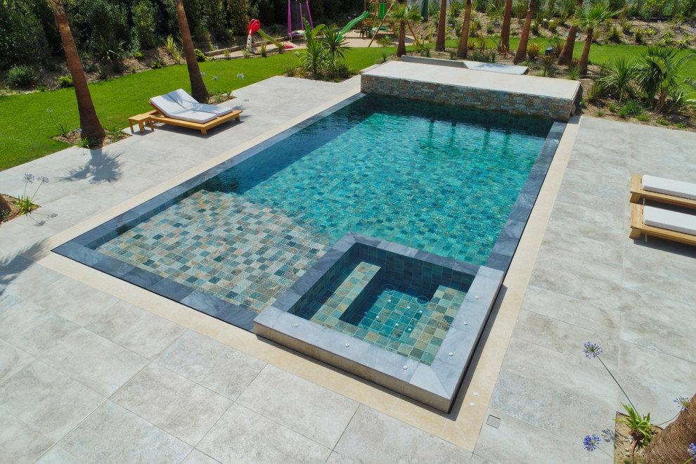 Ispirazione per una grande piscina a sfioro infinito design rettangolare davanti casa con paesaggistica bordo piscina e pavimentazioni in pietra naturale