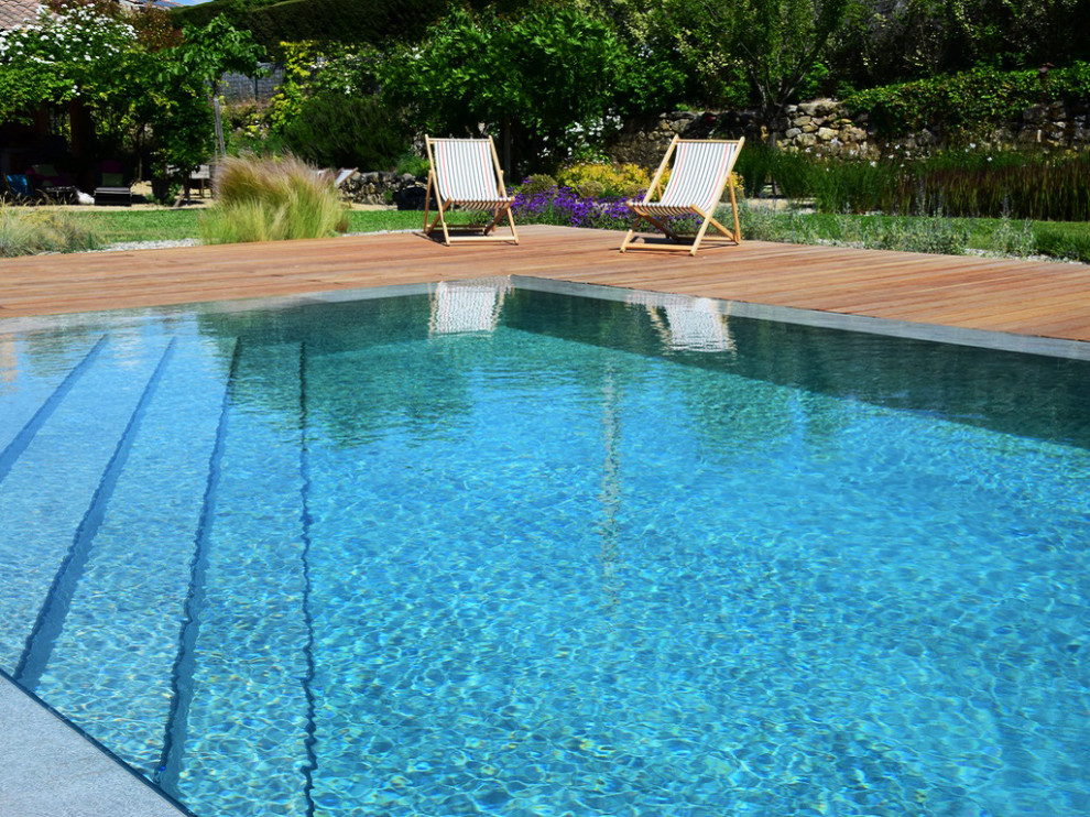 Idée de décoration pour une grande piscine à débordement design rectangle avec une terrasse en bois.