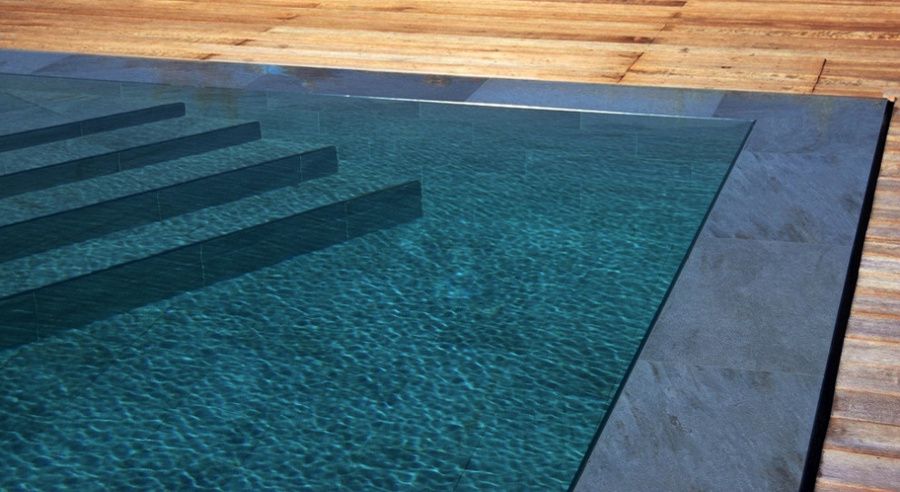 На фото: большой прямоугольный бассейн-инфинити в современном стиле с настилом с