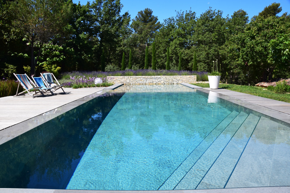 Immagine di un'ampia piscina a sfioro infinito minimal personalizzata con pedane