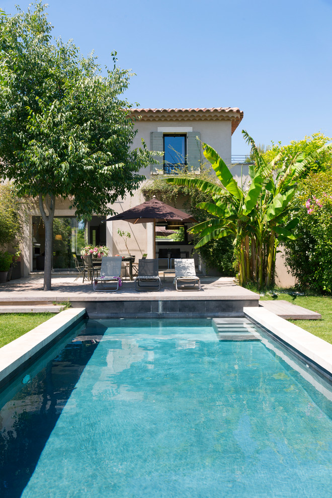 Imagen de piscina tropical rectangular en patio delantero con entablado