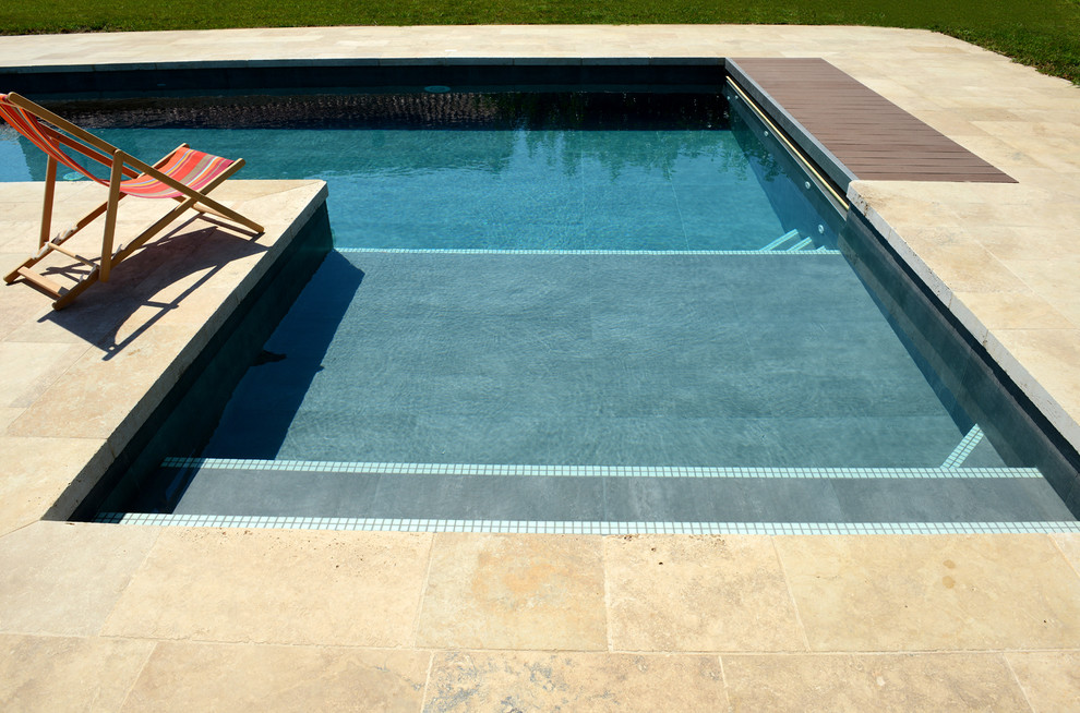 Imagen de piscina alargada contemporánea grande en forma de L en patio con suelo de baldosas