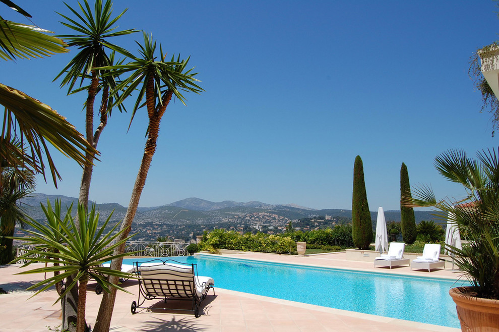 Diseño de piscina mediterránea extra grande rectangular en patio trasero con suelo de baldosas