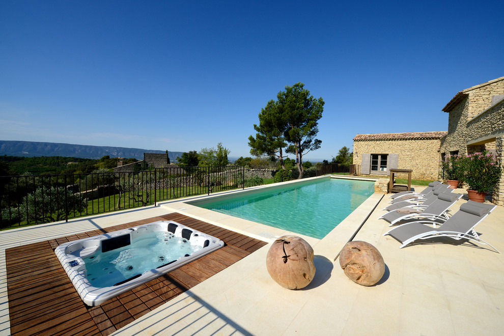Ejemplo de piscina alargada mediterránea extra grande rectangular en patio trasero con adoquines de piedra natural