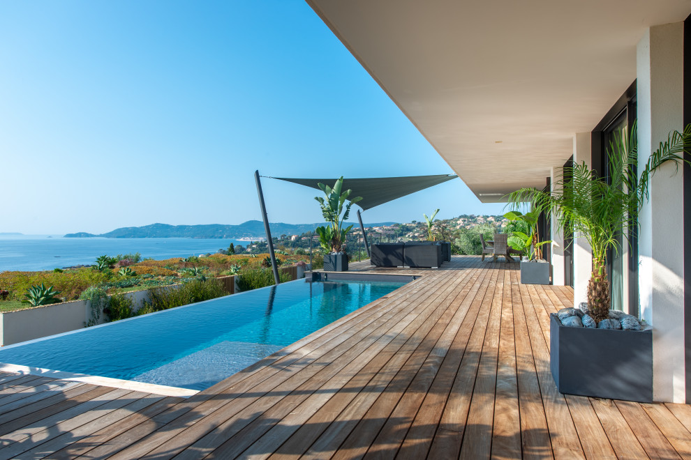 Idées déco pour une piscine à débordement contemporaine rectangle avec une terrasse en bois.