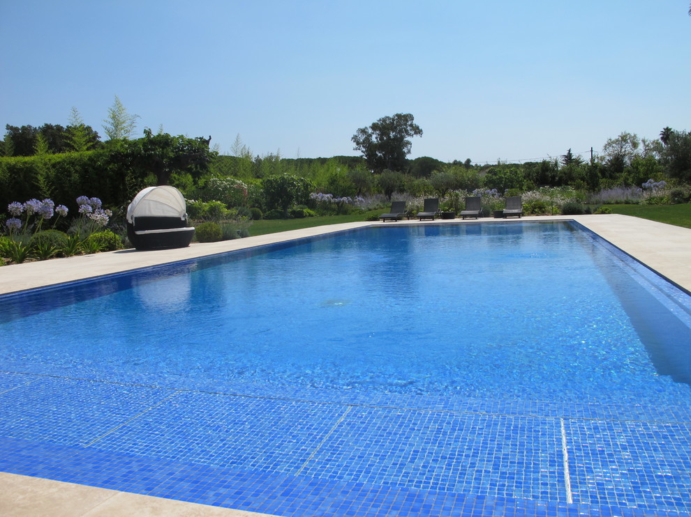 Aménagement d'une grande piscine à débordement et avant contemporaine rectangle avec des pavés en pierre naturelle.