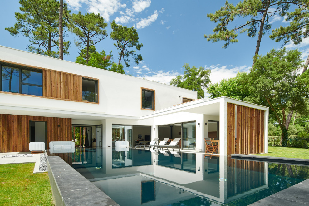 Ejemplo de piscina infinita contemporánea grande rectangular en patio trasero con losas de hormigón