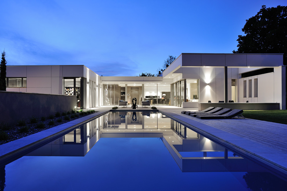Пример оригинального дизайна: большой прямоугольный бассейн на заднем дворе в современном стиле с настилом