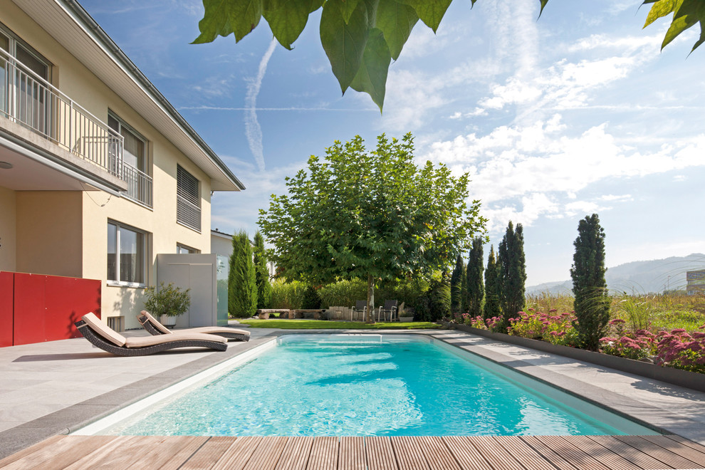 Cette image montre une piscine arrière nordique de taille moyenne et rectangle avec une terrasse en bois.