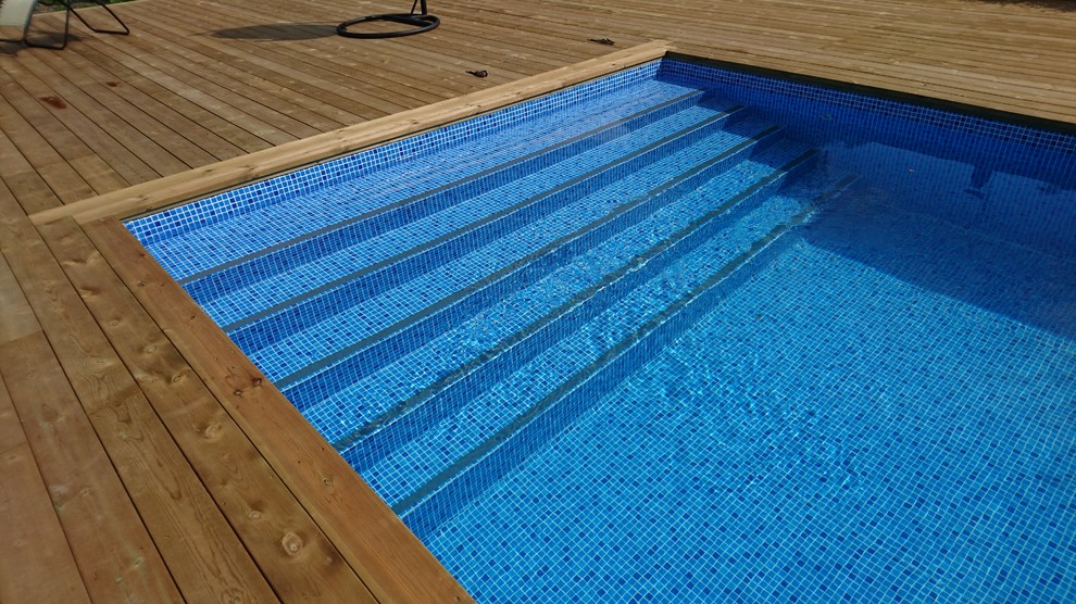 Réalisation d'une piscine arrière nordique de taille moyenne et sur mesure avec une terrasse en bois.