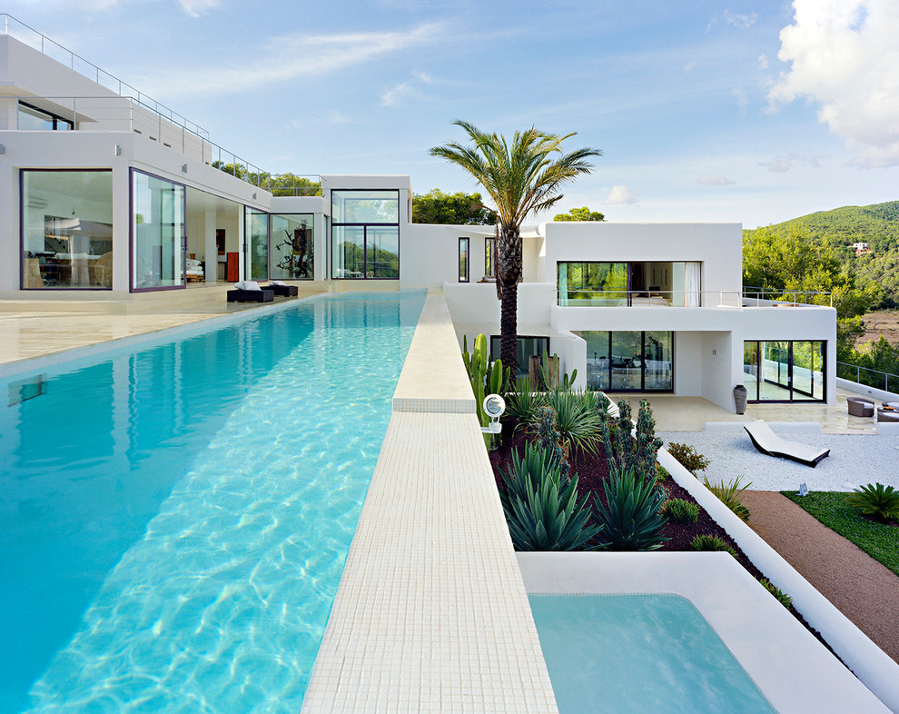 Modelo de piscina exótica grande rectangular en patio trasero con suelo de baldosas