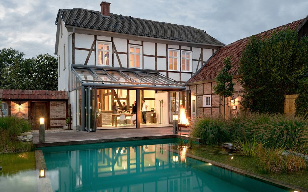 Modelo de piscina con fuente natural de estilo de casa de campo de tamaño medio rectangular en patio trasero con entablado