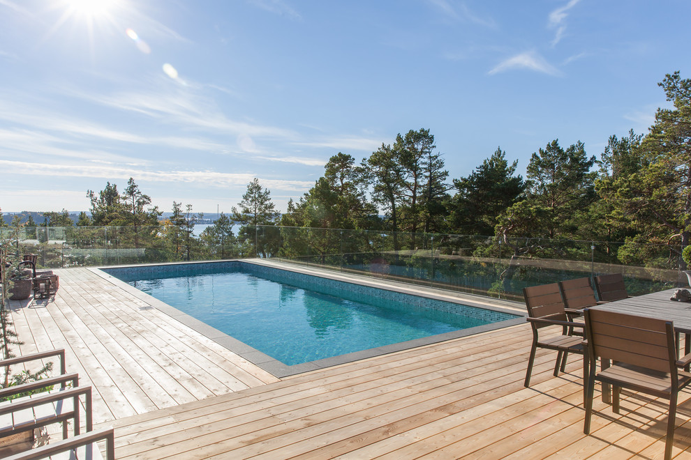 Idées déco pour une grande piscine scandinave rectangle avec une terrasse en bois.
