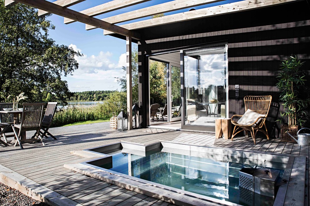 Aménagement d'une piscine latérale scandinave de taille moyenne et sur mesure avec un bain bouillonnant et une terrasse en bois.