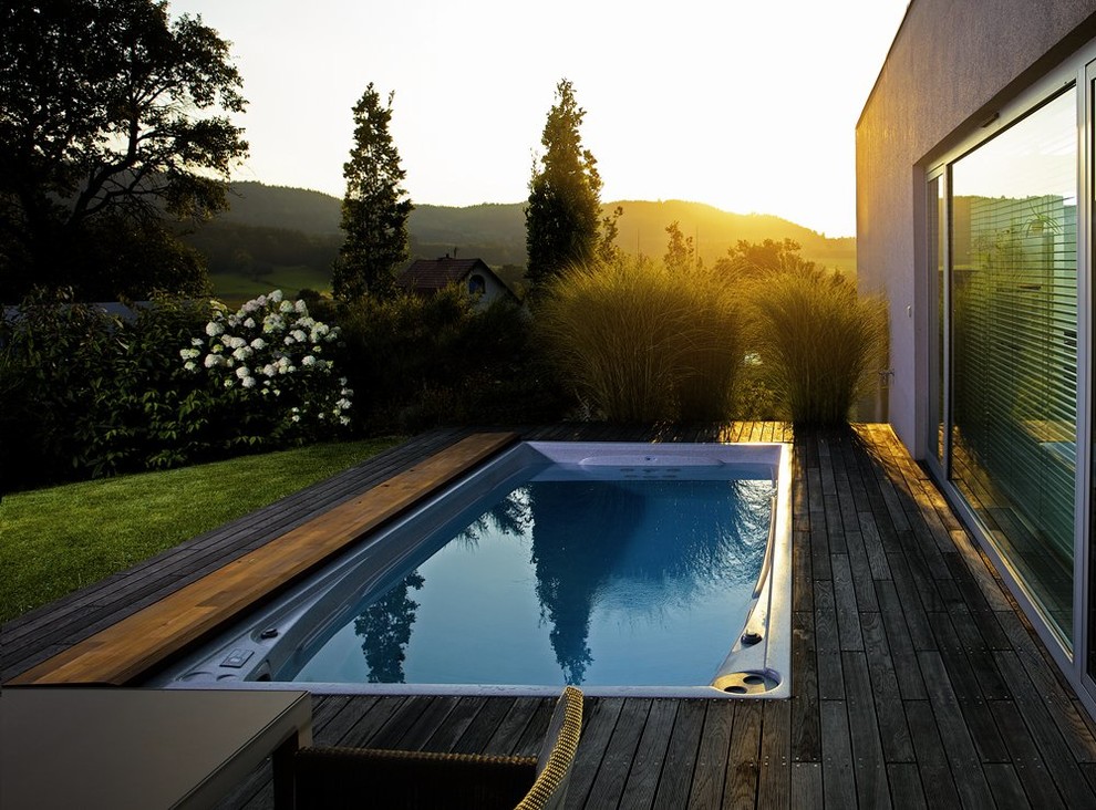 Стильный дизайн: прямоугольный бассейн среднего размера на заднем дворе в современном стиле с настилом - последний тренд