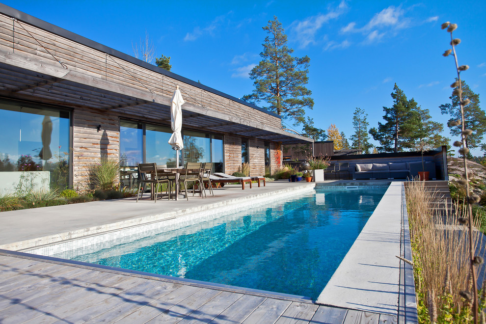 На фото: большой прямоугольный, спортивный бассейн на переднем дворе в скандинавском стиле с покрытием из бетонных плит с